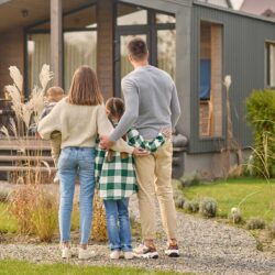 vista-posteriore-della-famiglia-che-abbraccia-e-ammira-la-propria-casa
